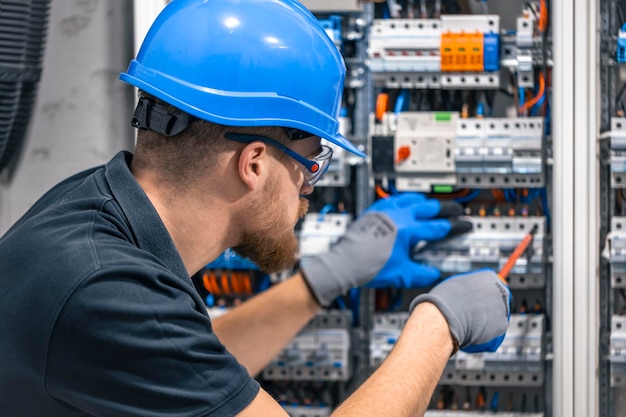 male-electrician-works-switchboard-with-electrical-connecting-cable_169016-52889