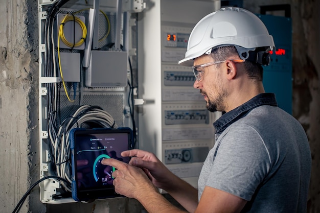 man-electrical-technician-working-switchboard-with-fuses-uses-tablet_169016-24004